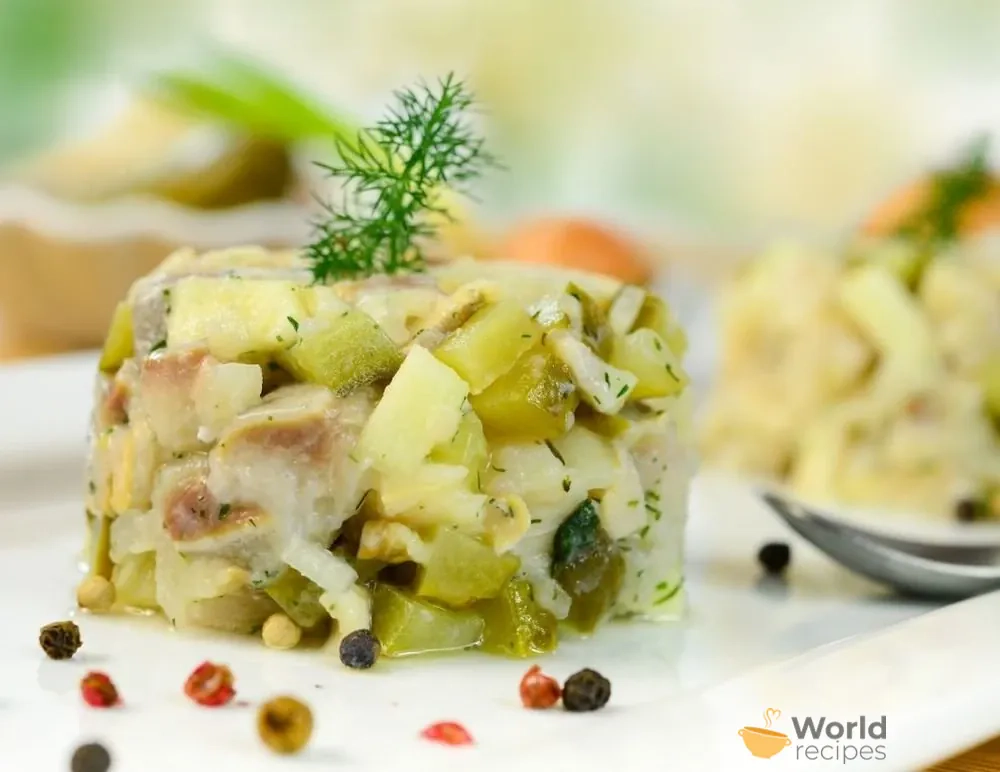 Vokiškos silkės salotos su bulvėmis, obuoliais, marinuotais agurkais ir konservuotais ananasais